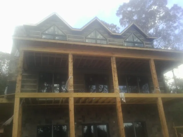 Dormers and porch framing on a large log home under construction — Roof Coating work by our crew in Giltner