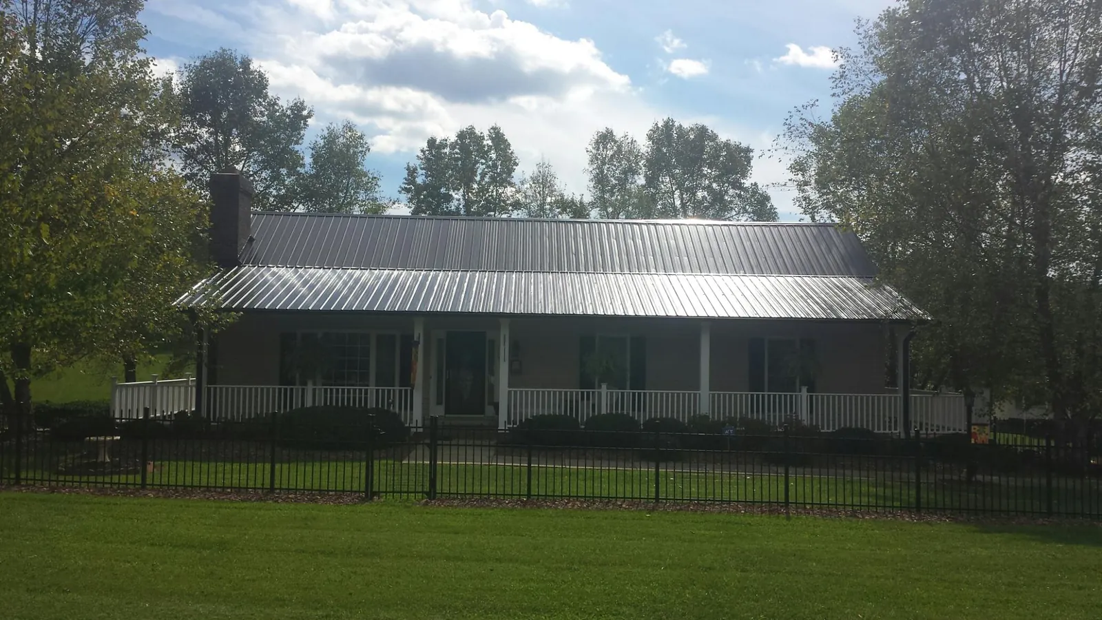 Gray metal roof on a brick ranch with a full width front porch — Gutter Guard Installation work by our crew in Giltner