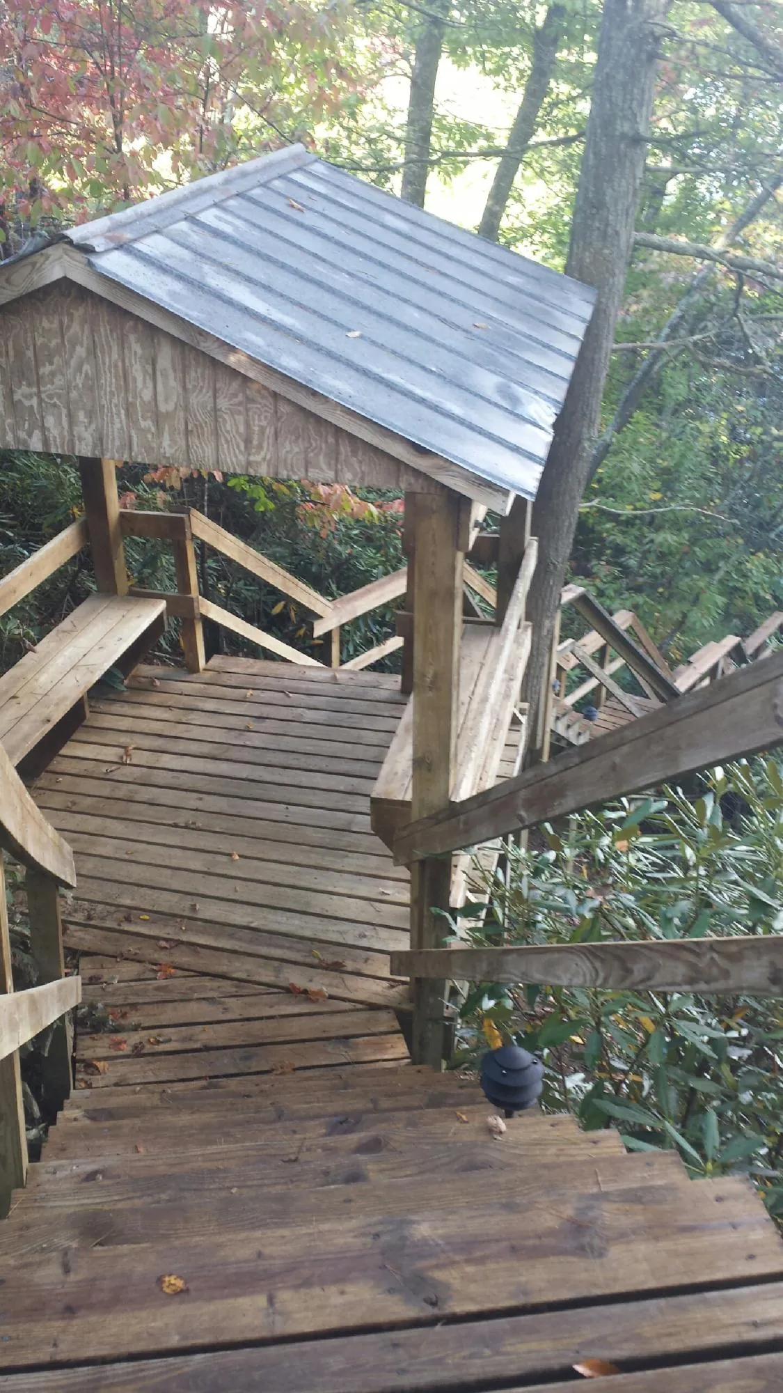 Metal roofed shelter over wooden steps on a wooded walkway — Skylight Repair & Installation work by our crew in Giltner