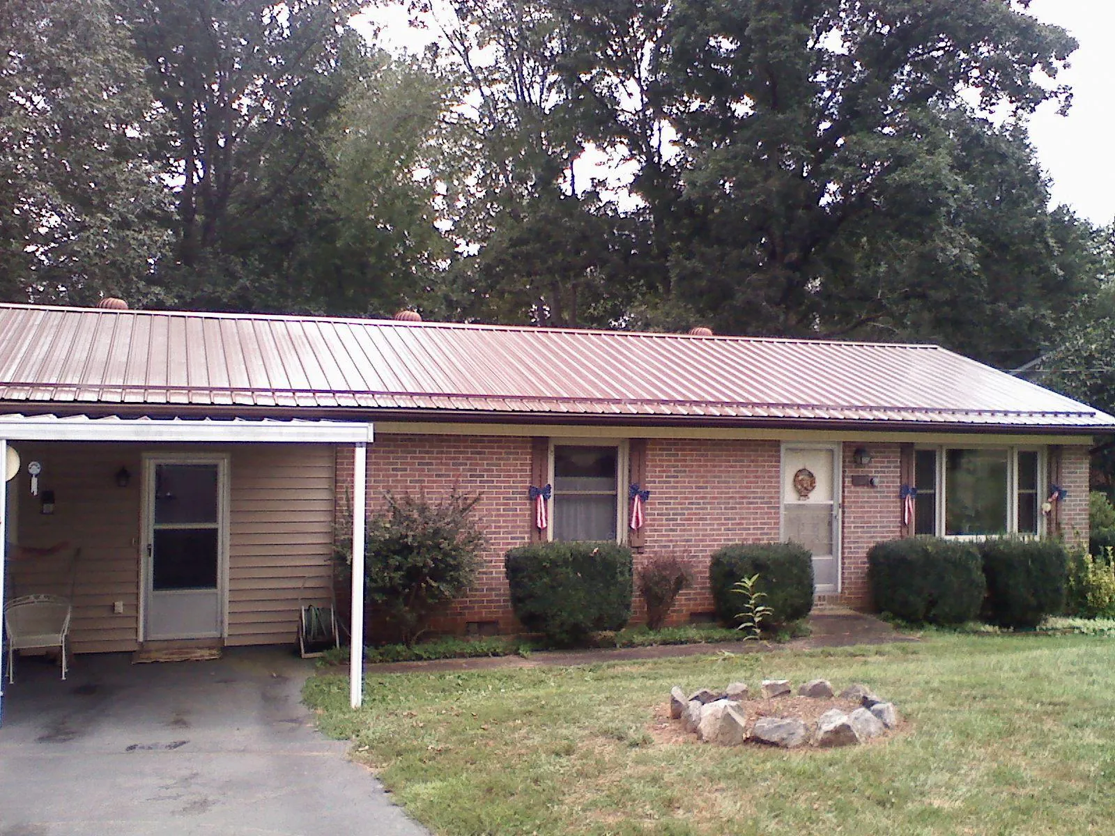 Bronze metal roof and carport on a brick ranch home — Roof Repair work by our crew in Giltner